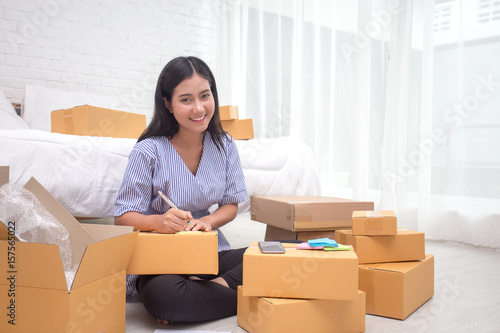 Young asian woman business owner work and white down address for deliver at home, woman business owner concept, 20-25 year old.