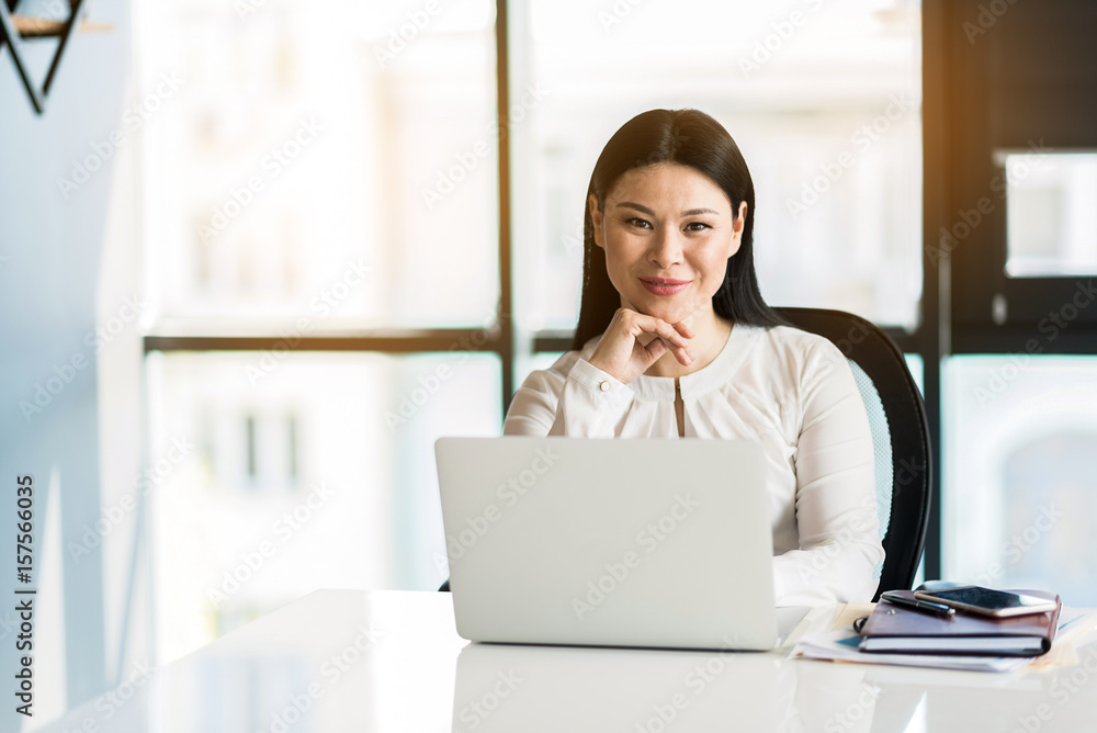 Positive charming lady sitting at her workplace Positive charming lady sitting at her workplace