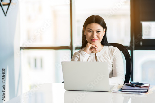Positive charming lady sitting at her workplace