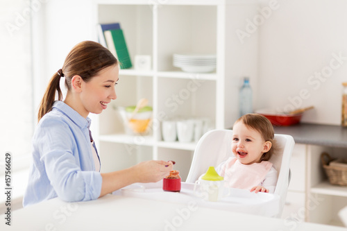 happy mother feeding baby with puree at home