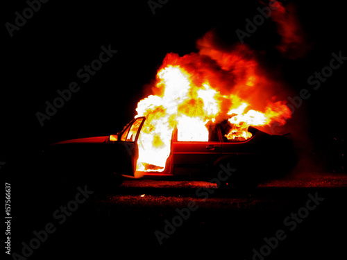 Burning car on the road in the night, burning man