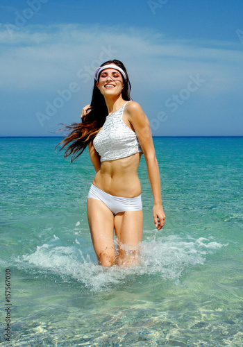 happy beautiful girl with fitness body running in sea water