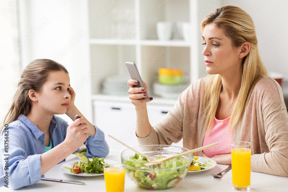 sad girl looking at her mother with smartphone