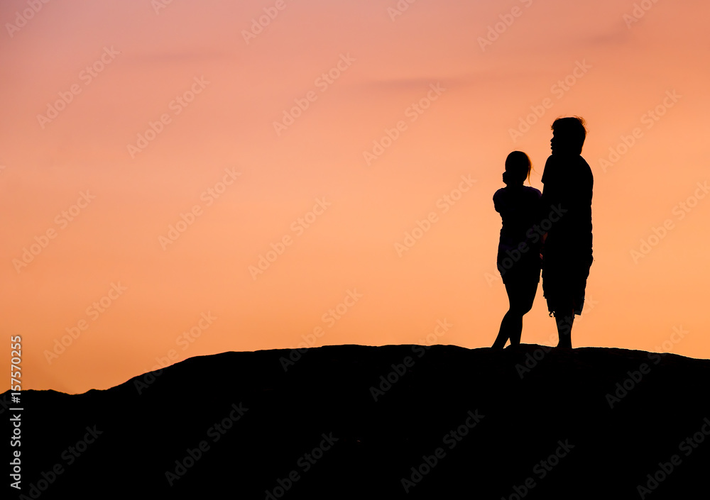 Couple on the beach silhoueete with sunset red sky.