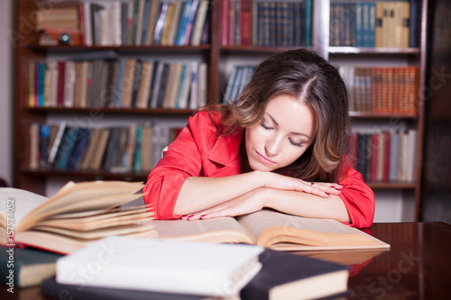 girl is preparing for the exam in the library reads books photo