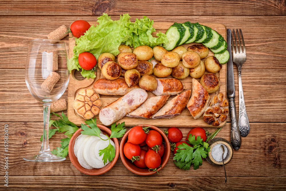 Grilled sausages and vegetables on the wooden board with wine glass. Grilled sausages and vegetables on the wooden board with wine glass.