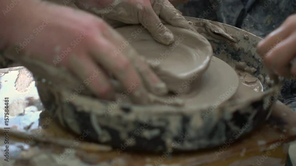 Potter trying to correct the mistake of pupil on pottery wheel in a workshop. Potter trying to correct the mistake of pupil on pottery wheel in a workshop.