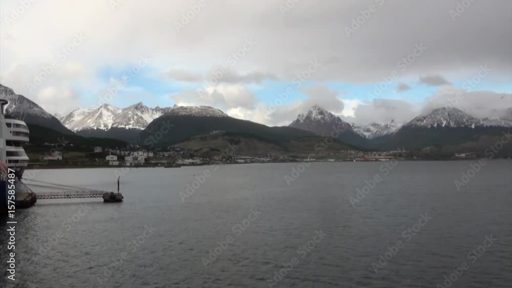 Cargo ship in port harbor on background of snow mountains. Place where ships moor at pier. Here you can take a boat and go to Antarctica. Rest and tourism in wild nature of ocean. Cargo ship in port harbor on background of snow mountains. Place where ships moor at pier. Here you can take a boat and go to Antarctica. Rest and tourism in wild nature of ocean.