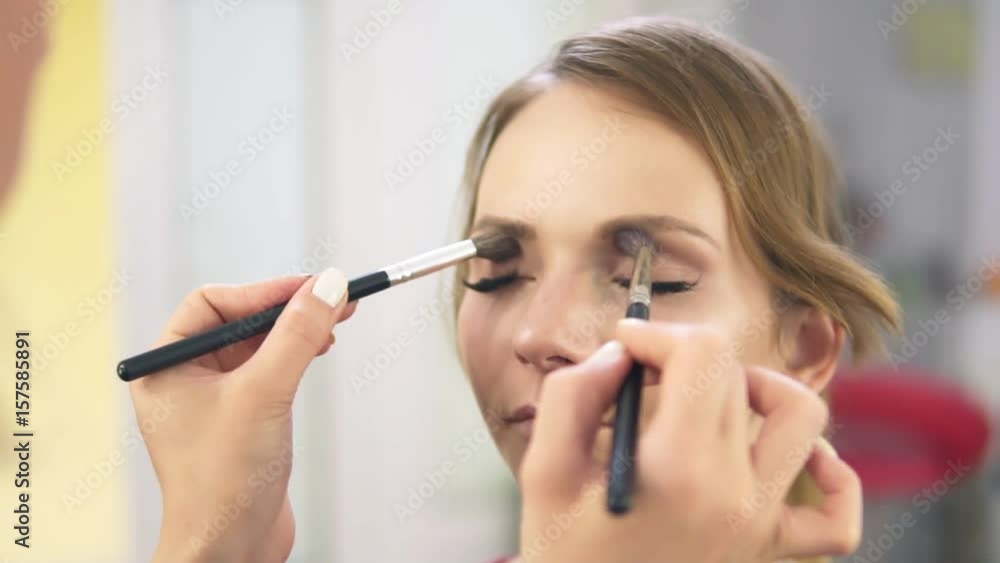 Closeup view of makeup artist applying eyeshadow on eyelid using makeup brush. Professional makeup. Slowmotion shot Closeup view of makeup artist applying eyeshadow on eyelid using makeup brush. Professional makeup. Slowmotion shot