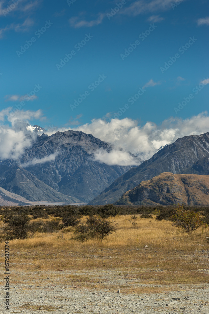 Middle Earth, New Zealand - March 14, 2017: Portrait of Snow capped High mountain range around Rock of Middle Earth under blue sky with white clouds. Set in a high desert mountainous scenery.