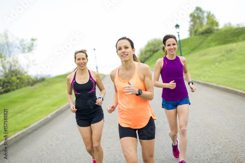 Three relaxed woman runners on a paved jogging daylight