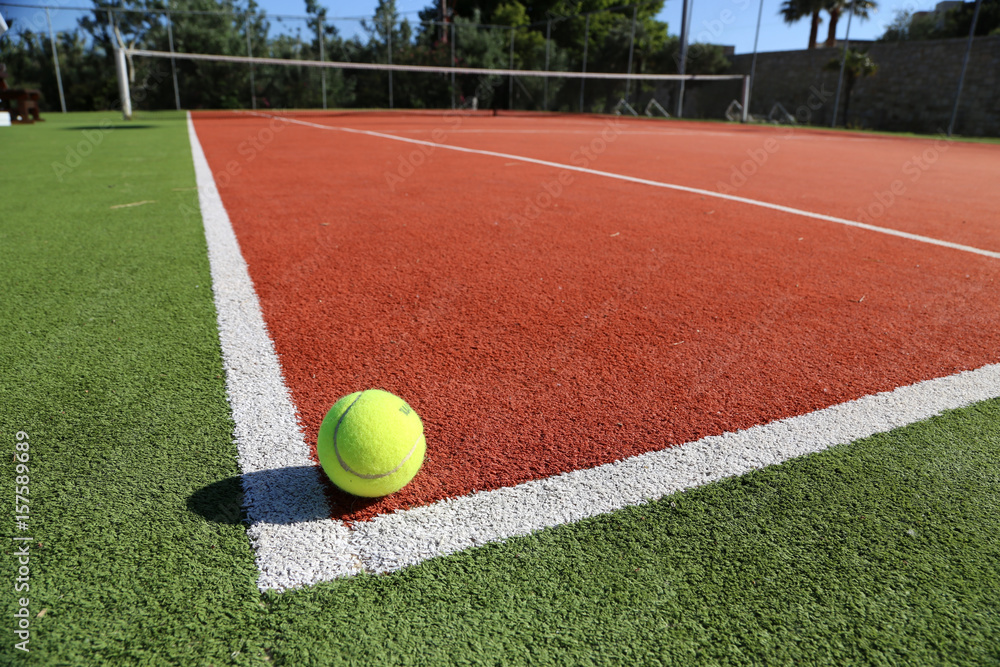Gelber Tennisball liegt auf weißer Linie auf Spielfeld, Symbolbild Tennis