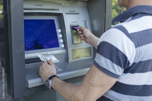 Man taking money from a cash machine using credit card. Cash widrow and finance concept