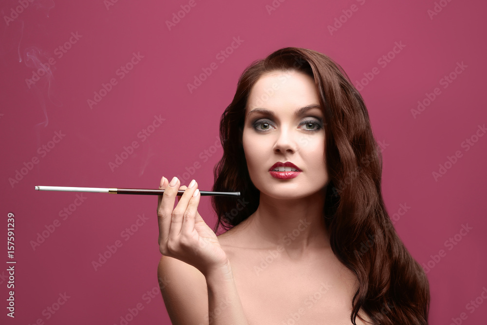 Obraz premium Beautiful woman smoking cigar on color background