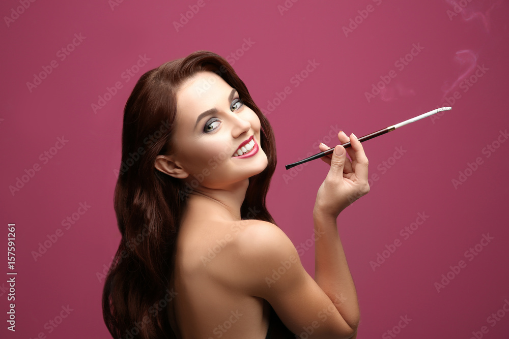Obraz premium Beautiful woman smoking cigar on color background