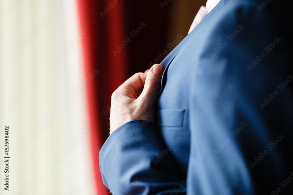 Man in blue suit two bottons, doing button, close up