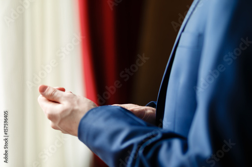 Man in blue suit two bottons, doing button, close up © korchemkin