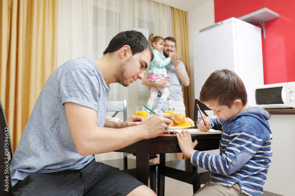 Male gay couple with children having breakfast in kitchen Male gay couple with children having breakfast in kitchen