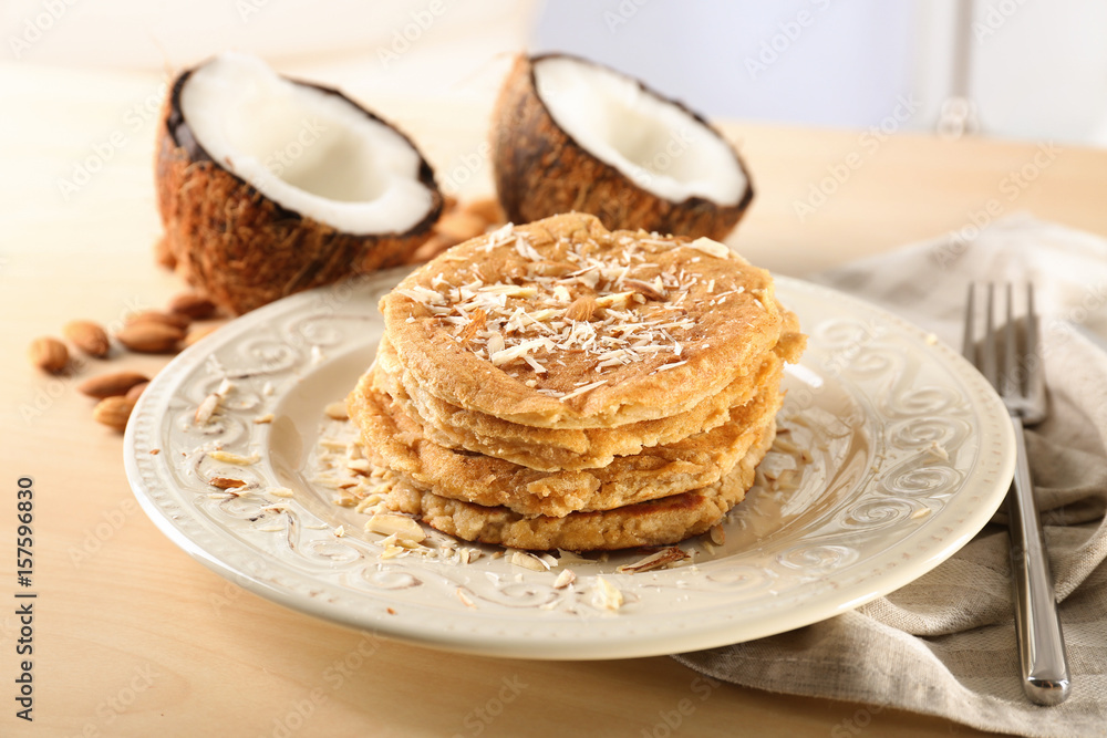 Delicious coconut pancakes decorated with almond shavings on table