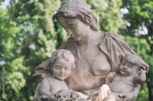 Young mother with little children monument on a tomb at a graveyard