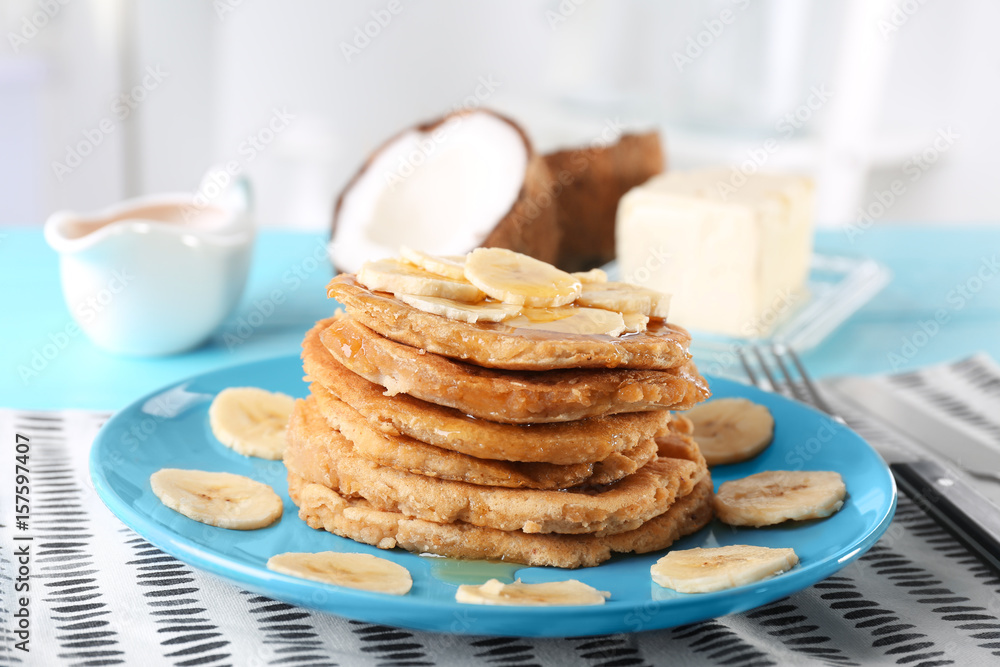 Stack of delicious coconut pancakes with sweet sauce and sliced banana on table Stack of delicious coconut pancakes with sweet sauce and sliced banana on table