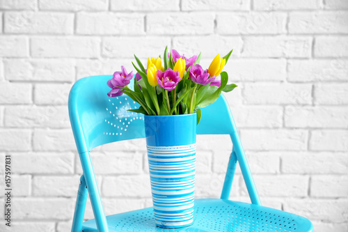 Vase with bouquet of beautiful tulips on chair