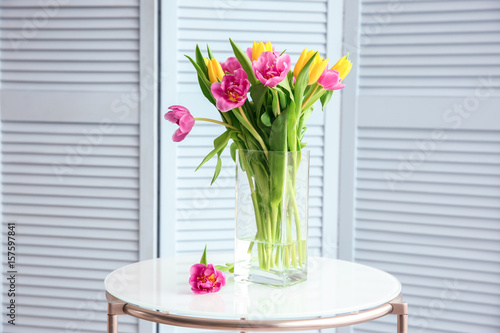 Glass vase with bouquet of beautiful tulips on table