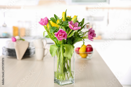 Glass vase with bouquet of beautiful tulips on table