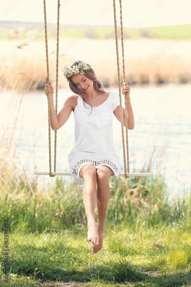 Beautiful young woman on swing near river Beautiful young woman on swing near river