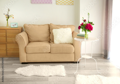 Interior of light room with beautiful peonies and eustoma flowers in vase on table