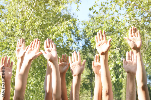 Young people putting hands in air together outdoors. Volunteering concept