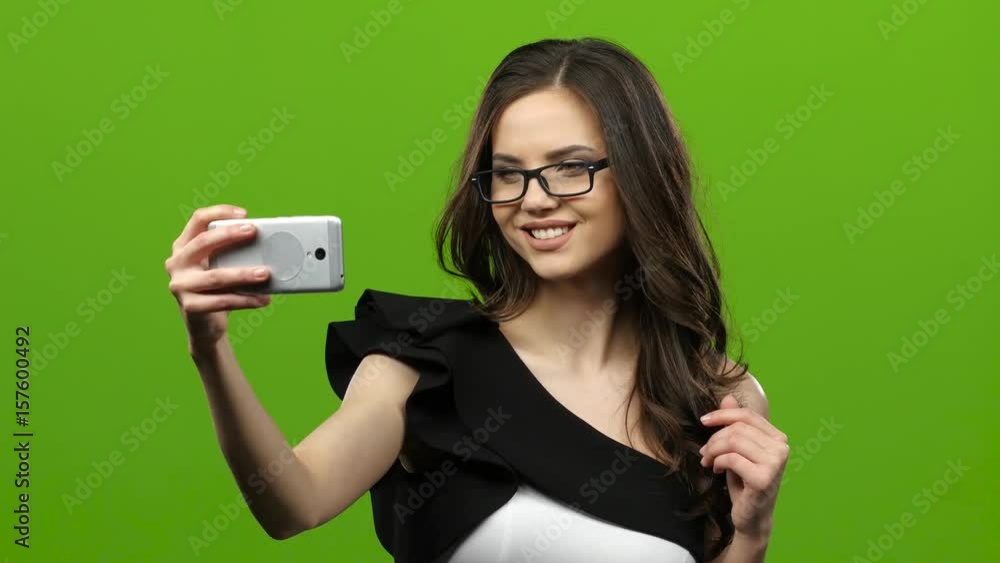 Girl of with a smartphone in her hands makes selfie. Green screen