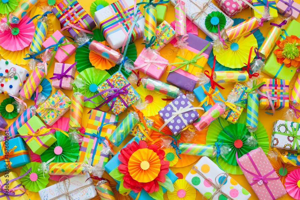 Celebratory crackers with confetti and bright gifts on a yellow background.