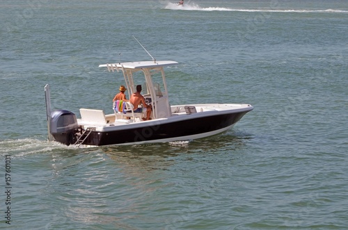 Young couple enjoying a leisurely saturday afternoon cruise on the florida intra-coastal waterway off Miami Beach in an outward engine powered blue motorboat with white trim.
