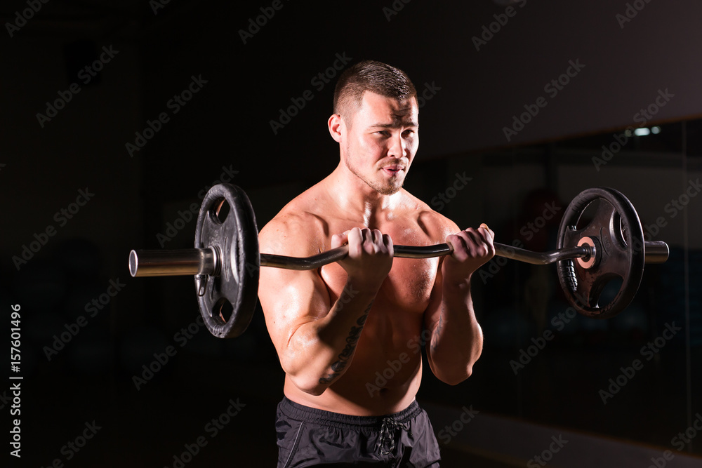 Sporty man doing exercises with barbell on dark background Sporty man doing exercises with barbell on dark background