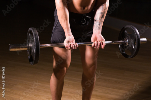 Muscular man working out in gym doing exercises with barbell close-up, strong male naked torso abs.