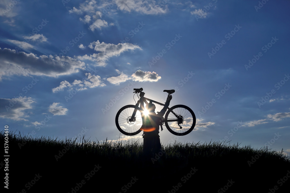 silhouette of a cyclist with a bike in the sun.