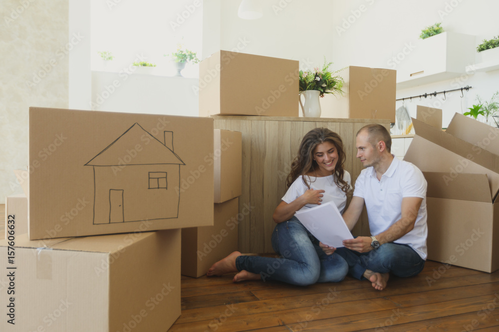Couple planning their new kitchen siting on the floor. young family moving to a new apartment and carrying boxes Couple planning their new kitchen siting on the floor. young family moving to a new apartment and carrying boxes