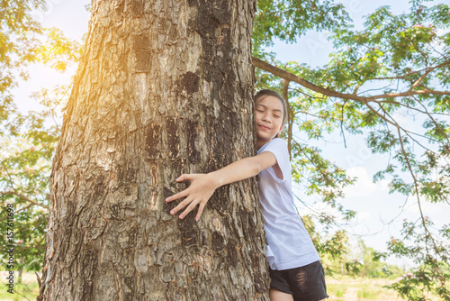 Young asian girl hugging tree trunk in park