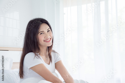 Beautiful asian woman sitting on bed in bedroom