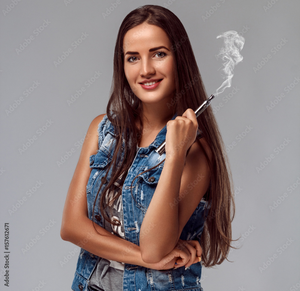 Obraz premium Young woman is smoking e-cigarette. Vape.