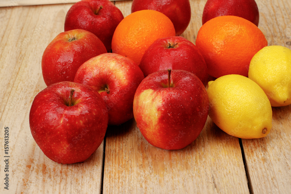 Apples lemons oranges with water drops on a white wooden background Apples lemons oranges with water drops on a white wooden background