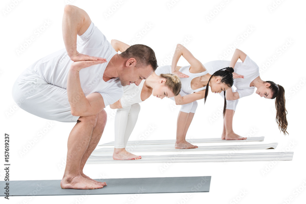 Young women with trainer practicing Revolved chair yoga pose on mats