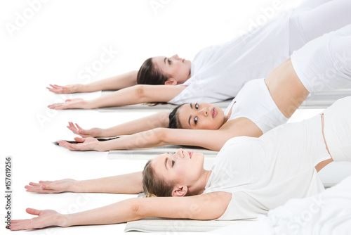 side view of group of young women doing yoga position isolated on white