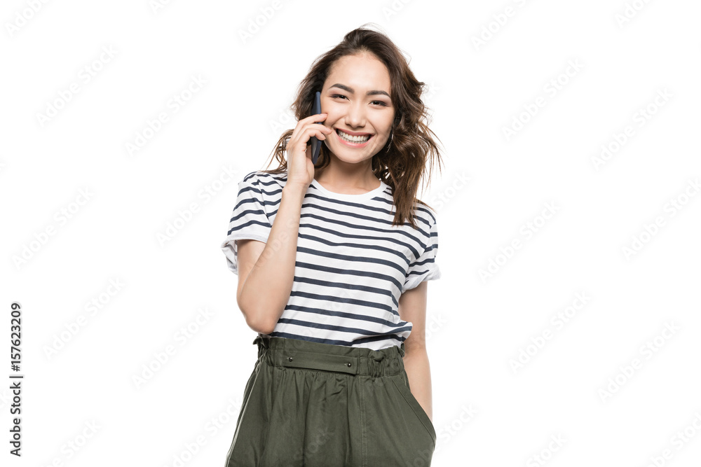 Smiling young woman talking on smartphone and looking at camera Smiling young woman talking on smartphone and looking at camera