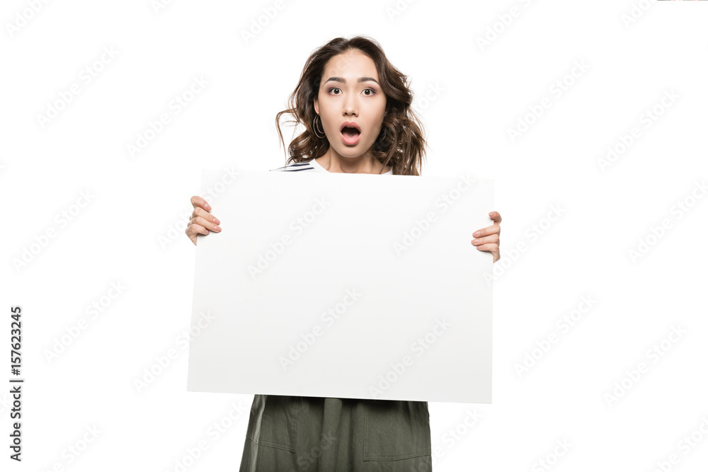 Shocked young woman holding blank white card and looking at camera Shocked young woman holding blank white card and looking at camera
