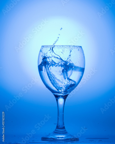 a wine glass with water drops on blue background.