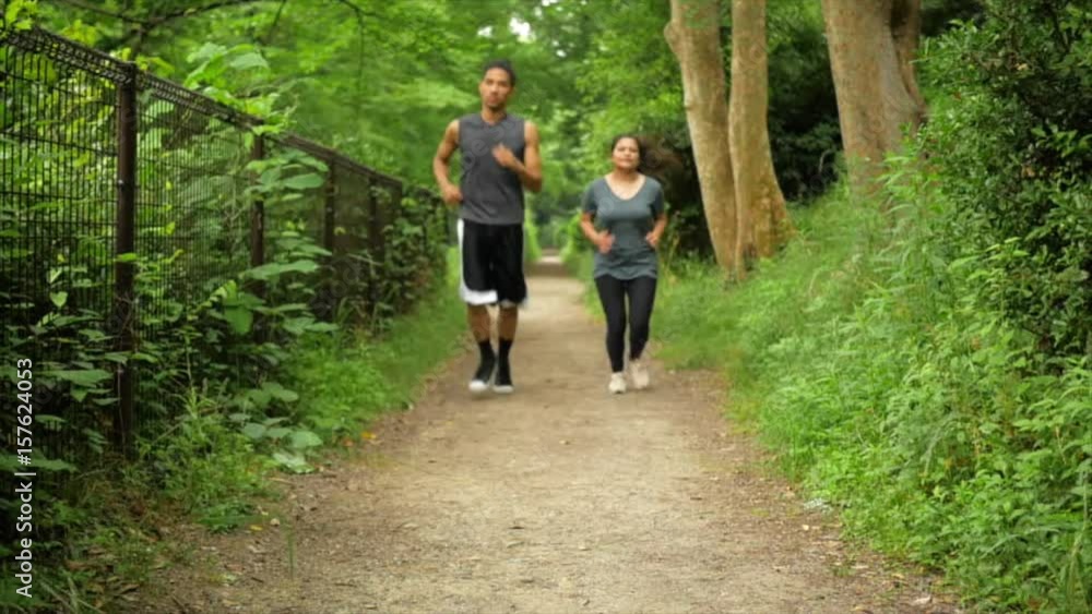 Two international friends run up a lush green path in slow motion. Two international friends run up a lush green path in slow motion.
