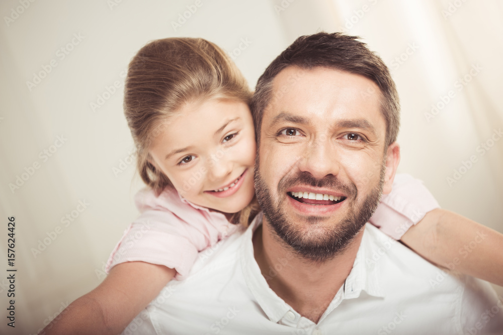 Close-up portrait of happy father and daughter hugging and smiling at camera