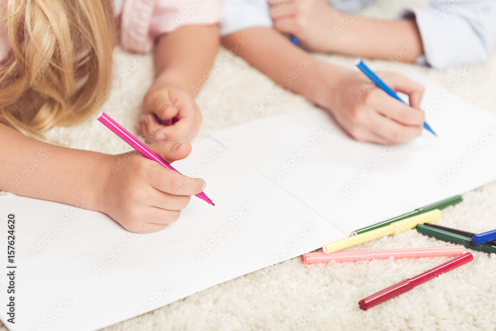 cropped shot of kids writing with felt pens on blank paper sheet at home cropped shot of kids writing with felt pens on blank paper sheet at home